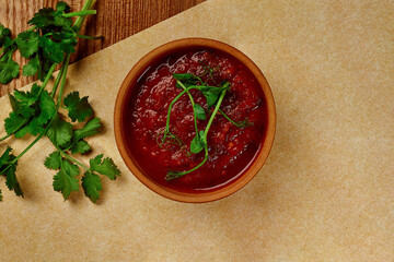Traditional georgian tomato sauce Satsebeli with cilantro, onion and garlic in clay bowl