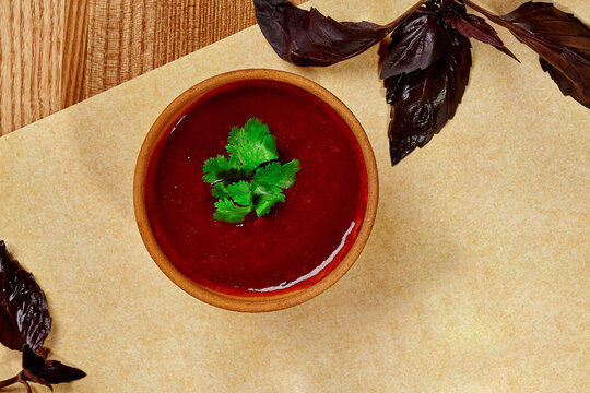 Traditional Georgian plum tkemali sauce in clay bowl with greens