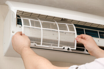 The master installs a clean air conditioner filter after purging. Maintenance of air conditioners, dust removal.