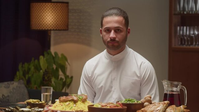 Portrait of young middle eastern man. Wearing traditional Islamic male clothes. Religious holiday Ramadan, holy month, iftar family dinner at home. Worship and culture concept.