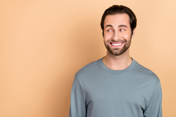 Photo of young cheerful guy wonder guess thoughtful look empty space plan isolated over beige color background