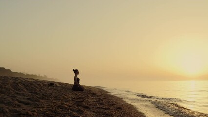 Focused woman practicing meditation on beach. Yoga woman sitting lotus pose.