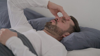 Fototapeta na wymiar Man having Headache while Sleeping in Bed
