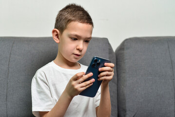 Kid boy holding and watching in smartphone 