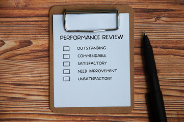 Top view of performance Appraisal checklist on clip board with pen and wooden cover background.