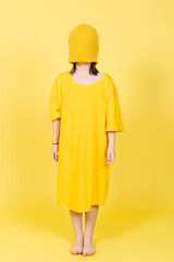 Abstract concept of anxiety, depression and stress on childhood concept. Little girl wearing over size shirt and blindfolded with hat isolated on yellow background