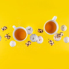 conceptual photo, flying cookies and two cups of tea on a yellow background.copy space