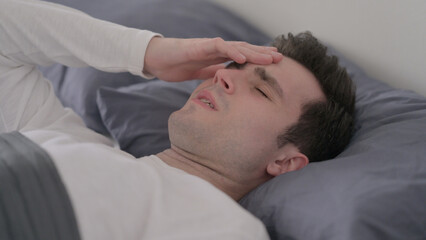 Fototapeta na wymiar Man having Headache while Sleeping in Bed, Close up