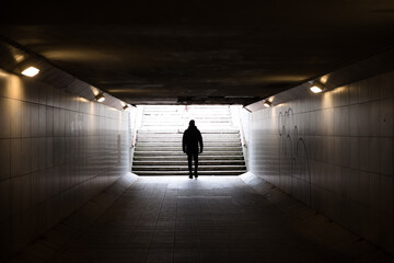Man walking in dark underground tunnel. Stranger anonymous person. Unknown person in subway. Horror...