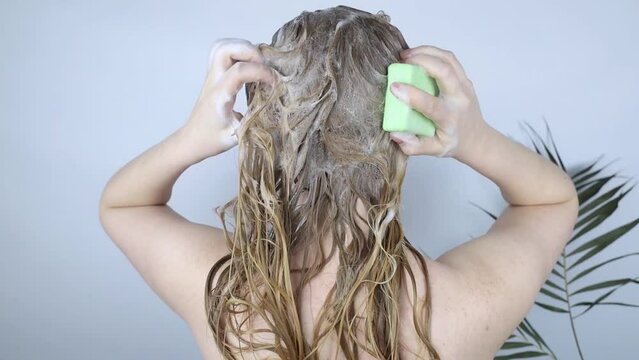 Solid hair shampoo. Close-up of a blonde girl in the bathroom, which lathers her hair with dry shampoo. Lots of foam and peek effect.