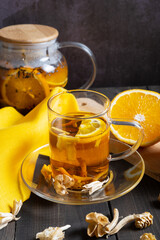 A glass teapot and a cup of hot orange fruit tea. Warming aromatic drink.
