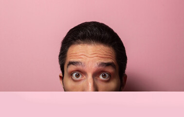 look half face on a pink background. A surprised look on a man's face. A vivid display of emotion