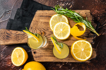 Italian limoncello liqueur and fresh lemons on a rustic wooden board. Dark background. Top view. Copy space - obrazy, fototapety, plakaty