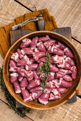 Raw chicken hearts in a wooden plate with herbs. Organic offals. Wooden background. Top view