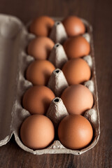Closeup natural and organic chicken eggs in craft paper box on brown wooden table