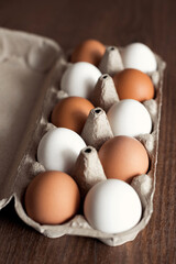 Top view of mixed natural and organic chicken eggs brown and white in craft box on wooden table