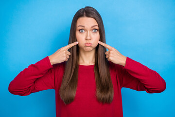 Photo of millennial impressed long hairdo lady index cheeks wear red sweater isolated on blue color background