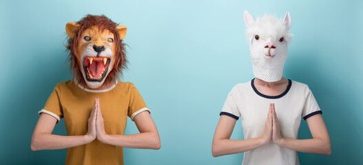 Young woman in lion and alpaca mask hold their hands together in gratitude or prayer sign, isolated...