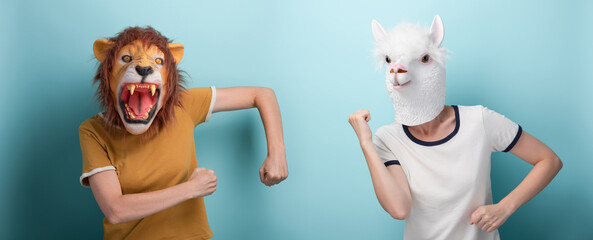 Young woman in lion and alpaca mask perform cheerful carefree party dance moves, isolated on blue background.
