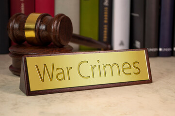 Gavel and law book with sign and war crimes on a wooden table