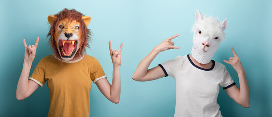 Woman in lion and alpaca mask with hands in rock sign, isolated on blue background