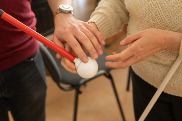 A man shows a woman a tactile cane with a round tip. 