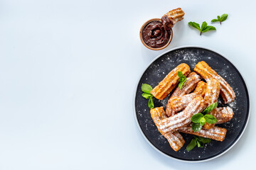 Fried churros with chocolate sauce and mint. Spanish sweets for breakfast