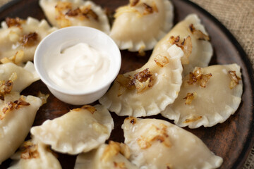 dumplings with potatoes and onions with sour cream in the center of the plate
