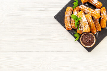 Plate with fried churros and chocolate sauce, top view