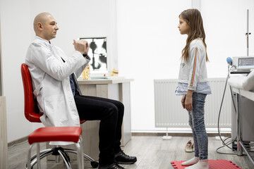 Physical therapist examines little girl in detail for musculoskeletal disorders in medical office....