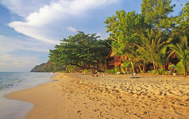 Ko Chang, Thailand - December 7. 2018: View on tropical white sand beach with green trees and wood bamboo houses