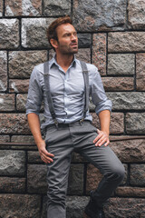 Obraz premium Portrait of an attractive male modeling infront of a grey stone wall