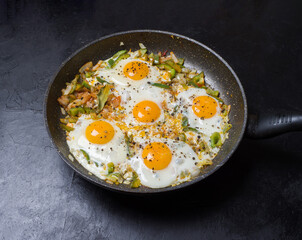 Fried eggs in a frying pan on a black background. Studio photography