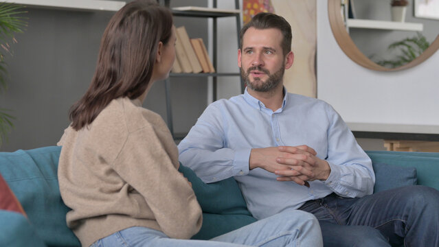 Couple Having Serious Conversation While Sitting On Sofa 