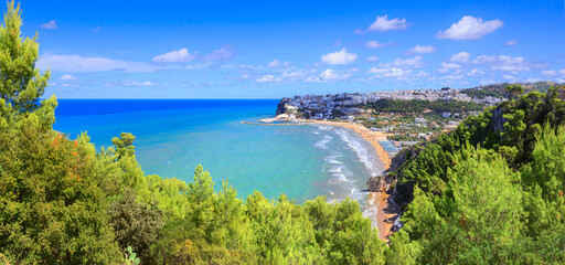 Bay of Peschici in Apulia, Italy: view of townscape and sandy beach. Peschici is famous town for its seaside resorts, its territory belongs to the Gargano National Park.