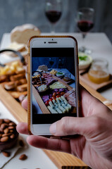 Taking photograph of food served on the table with your smartphone. Charcuterie. Picada Argentina