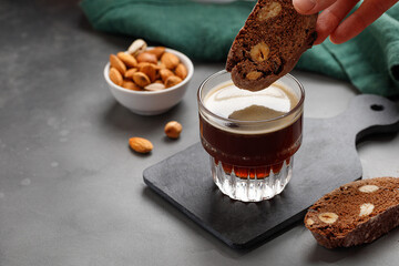 Woman's hand dips cookies in coffee. Biscotti cookies with almond and hazelnuts. - obrazy, fototapety, plakaty
