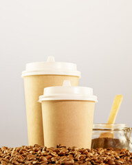 Coffee to go. Two disposable eco-friendly cardboard cups on a natural coffee beans on a light neutral background with copy space. Takeaway coffee concept