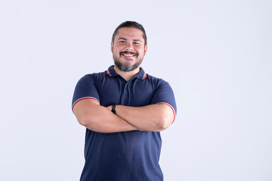 A confident smiling man of mixed race with arms crossed. Barrel chested guy in his Late thirties. Isolated against a white background.