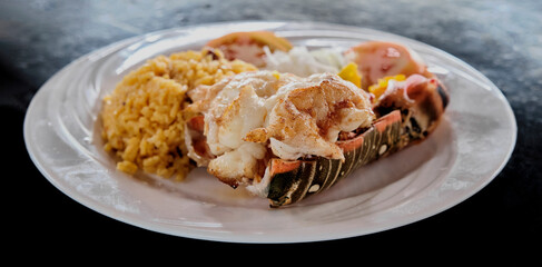 Baked lobster tail with yellow rice and vegetables.