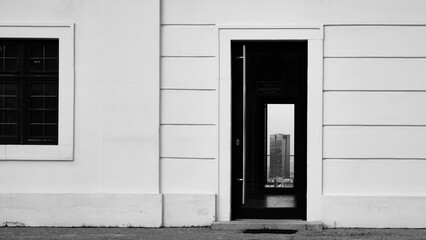 View of a skyscraper in the city through the glass doors of the facade of the house in front in black and white, Bratislava, Slovakia