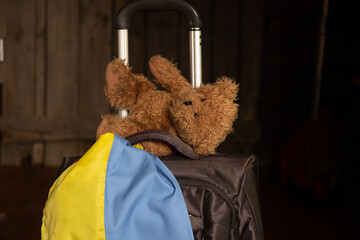 A suitcase and a teddy bear with the flag of Ukraine, leave their home because of the war,...