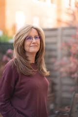 Fototapeta premium Mature white woman smiling in a happy attitude in the garden of her house.