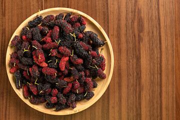 Mulberry on wood table background. hand holding Morus alba. ripe mulberry fruit.