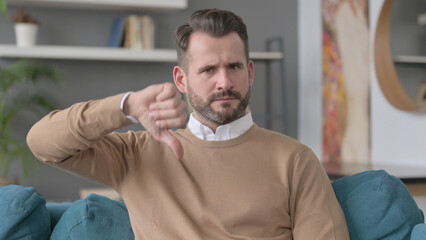 Portrait of Man showing Thumbs Down at Home 