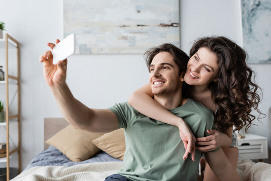 happy young couple taking selfie in bedroom.