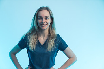 young blonde attractive nurse without a mask posing in front of a camera light blue background...