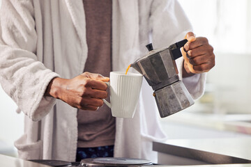 Cant start the day without some coffee. Shot of an unrecognizable man pouring coffee into a cup at home.