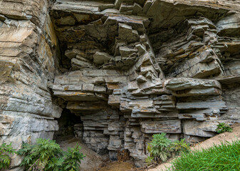 Fototapeta premium Secret cave in rocks. Rock wall with entrance to ancient cavern grotto