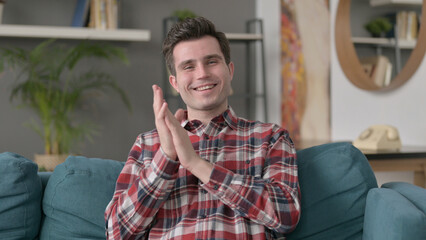 Portrait of Man Clapping while Sitting on Sofa 